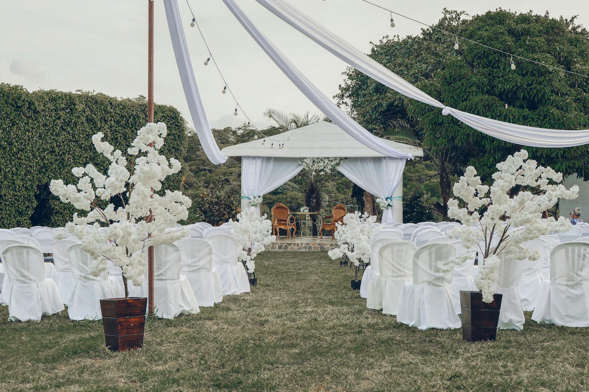 Outdoor wedding ceremony setup with white chairs and floral arch