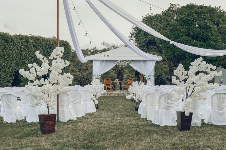 Outdoor wedding ceremony setup with white chairs and floral arch